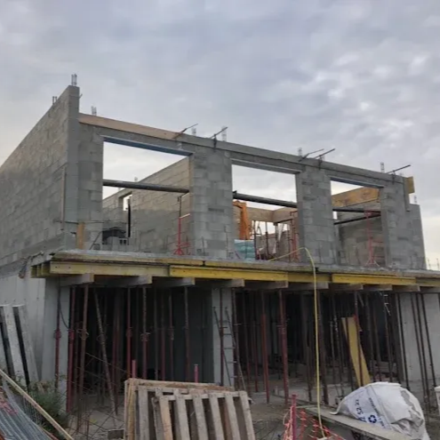 Bâtiment en béton partiellement construit, avec échafaudages et poteaux de soutien.