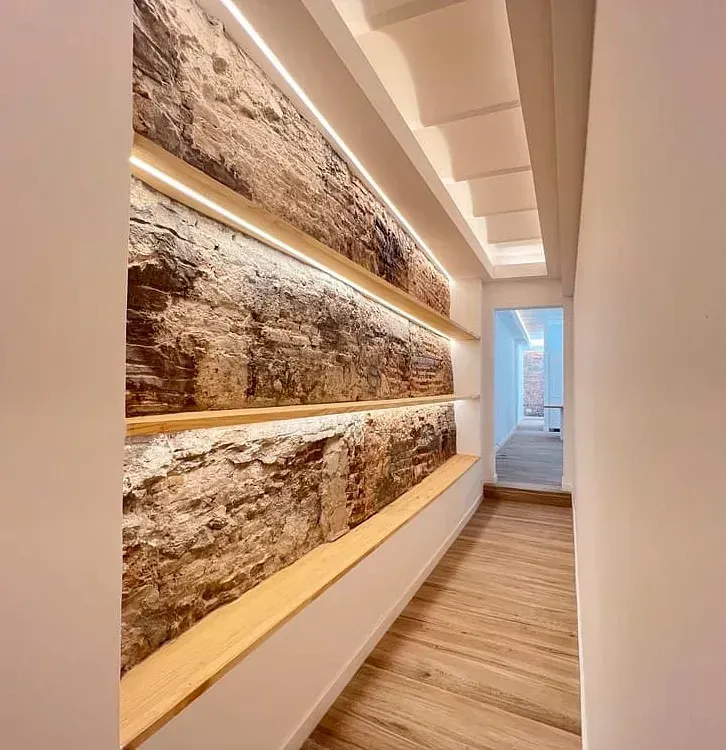 Un pasillo con una pared de ladrillos y estantes de madera.