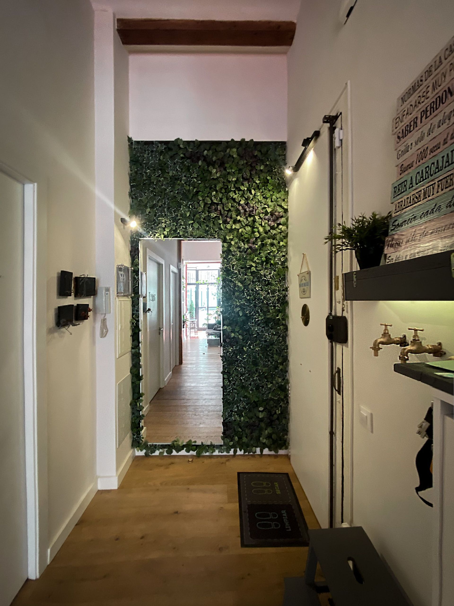 Un pasillo con una pared verde y un espejo.