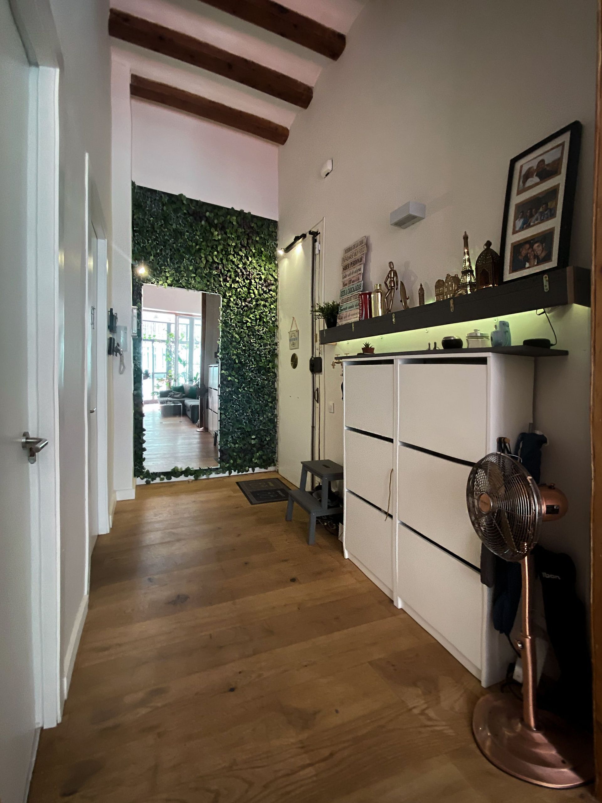 Un pasillo con suelos de madera y una pared verde.