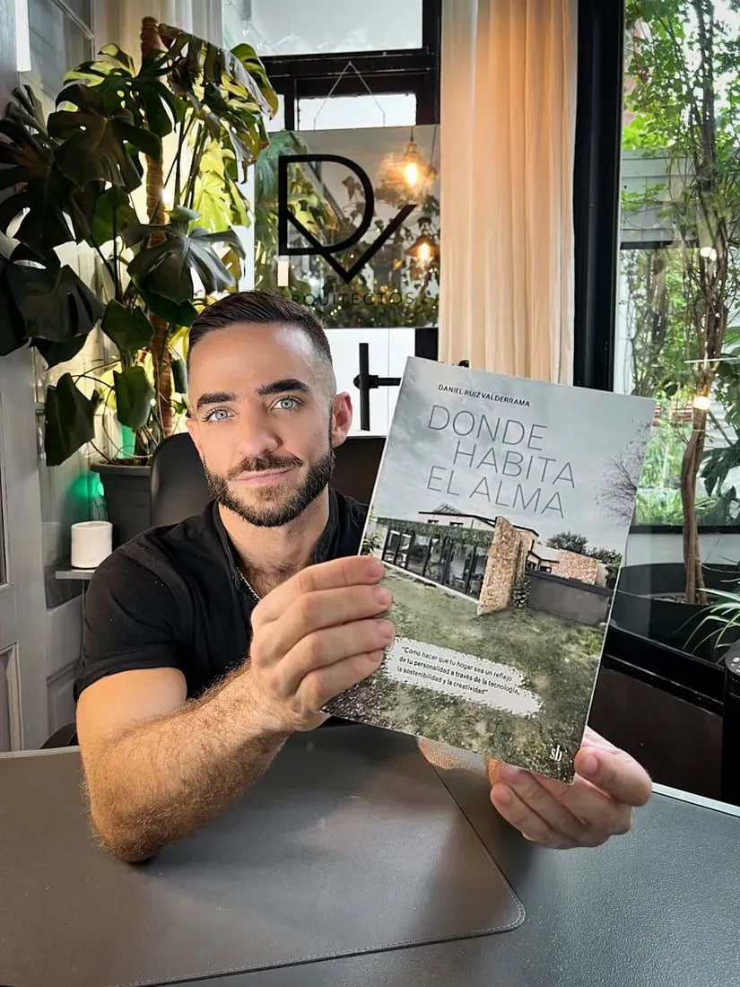 Un hombre con barba sostiene un libro en sus manos.
