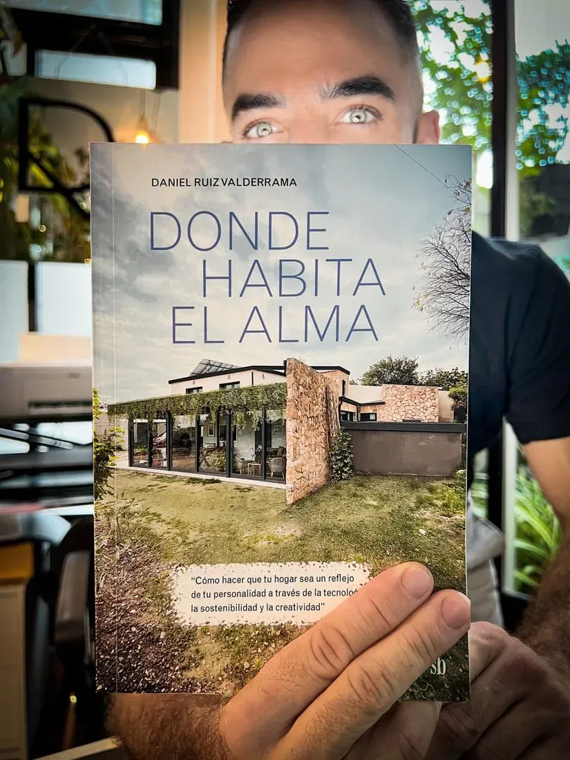 A man is holding a book titled donde habita el alma