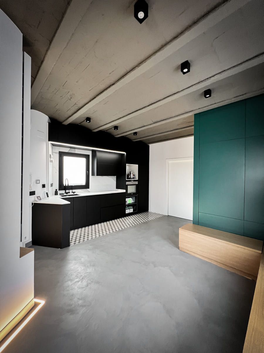 Una sala de estar con cocina y una pared verde.