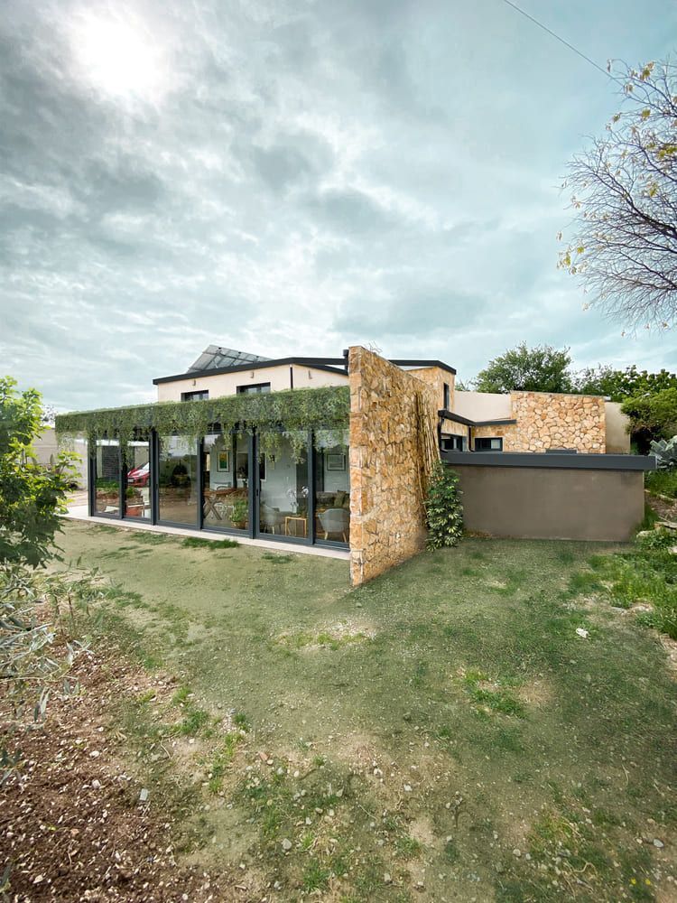 Una casa grande con muchas ventanas está situada encima de un exuberante campo verde.