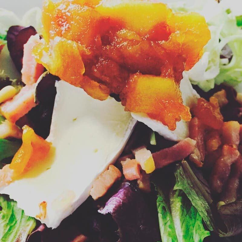 Un primer plano de una ensalada con un trozo de queso encima.