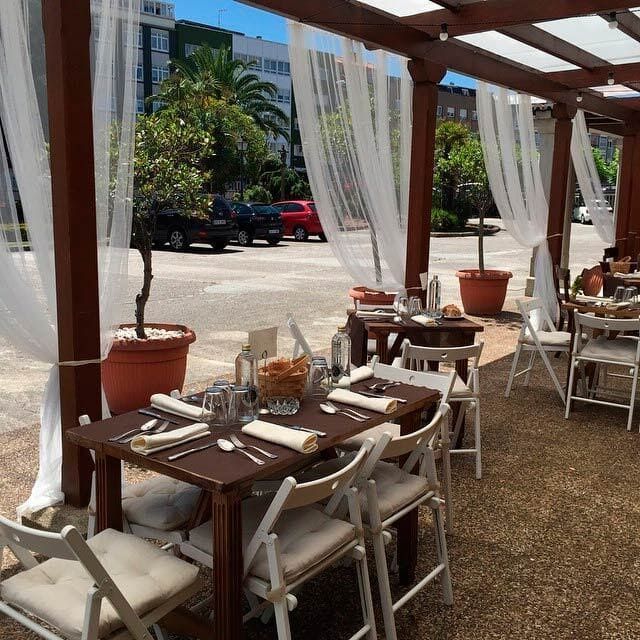 Mesas y sillas bajo un dosel con cortinas blancas.