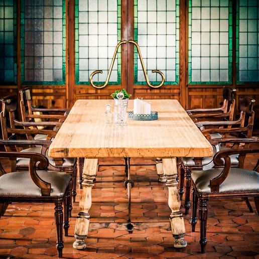 Una mesa y sillas de madera en una habitación con vidrieras.