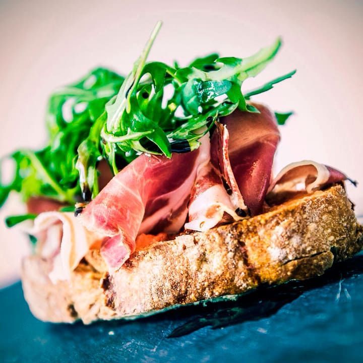 Un trozo de pan con carne y verduras encima.