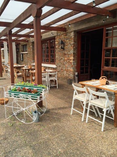 Un patio con mesas y sillas bajo una pérgola.