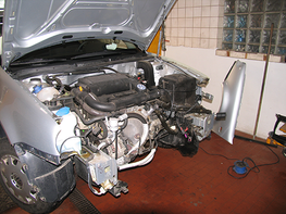 Ein silbernes Auto mit geöffneter Motorhaube und freiliegendem Motor