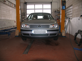Ein silbernes Auto steht auf einer Hebebühne in einer Garage
