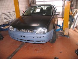 Ein schwarzes Auto steht auf einer Hebebühne in einer Garage.