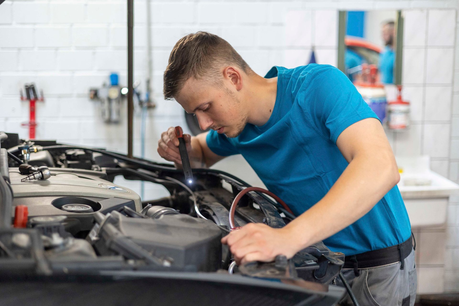 Ein Mann arbeitet in einer Garage am Motor eines Autos.