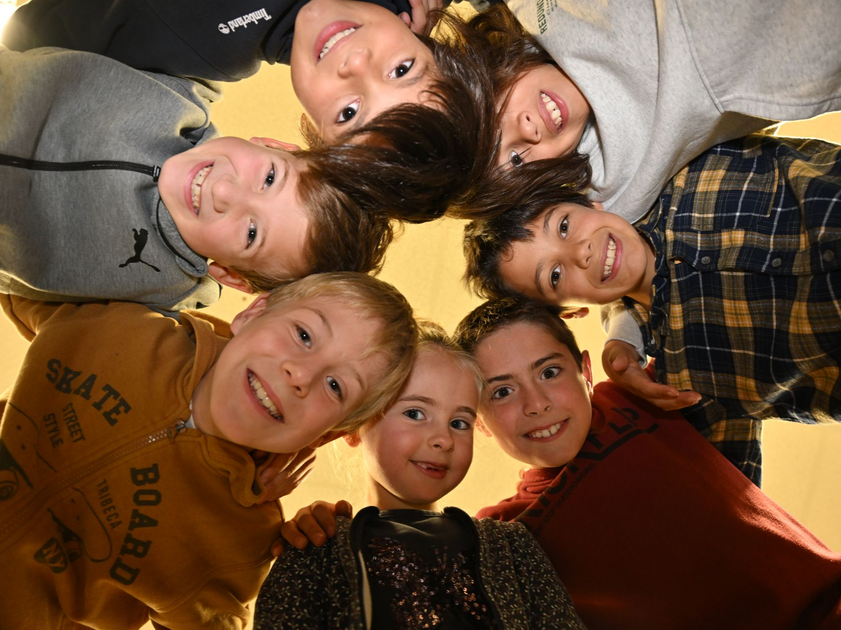 Groupe d’enfants formant un cercle vu d’en bas, avec leurs têtes rapprochées