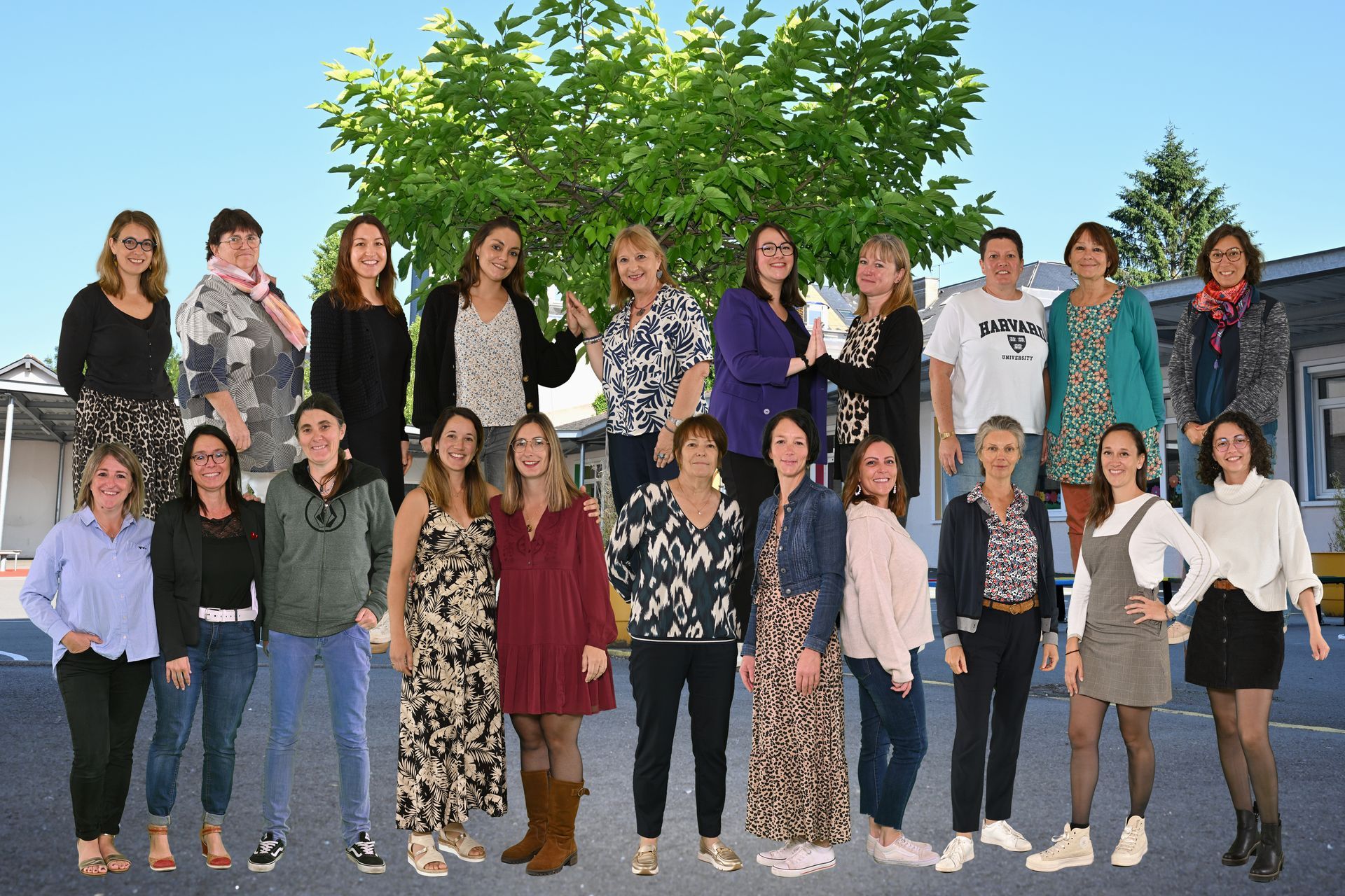 Groupe d’adultes debout en extérieur, disposés en deux rangées devant un arbre feuillu