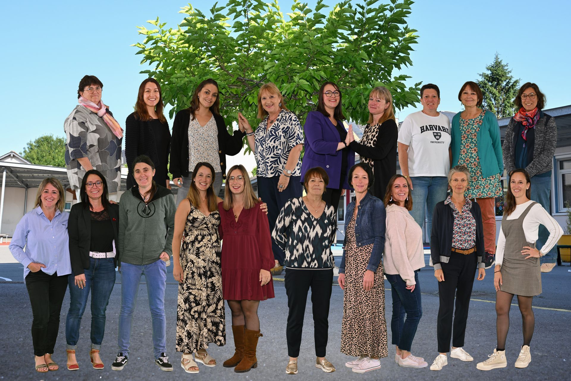 Groupe d’adultes debout en extérieur, disposés en deux rangées devant un arbre feuillu