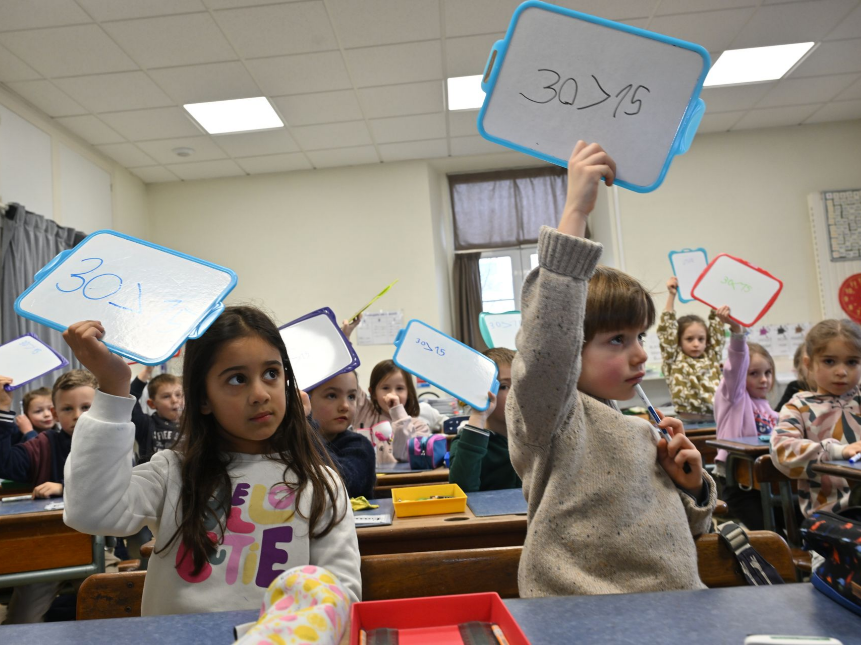 Élèves en classe levant des ardoises avec des calculs