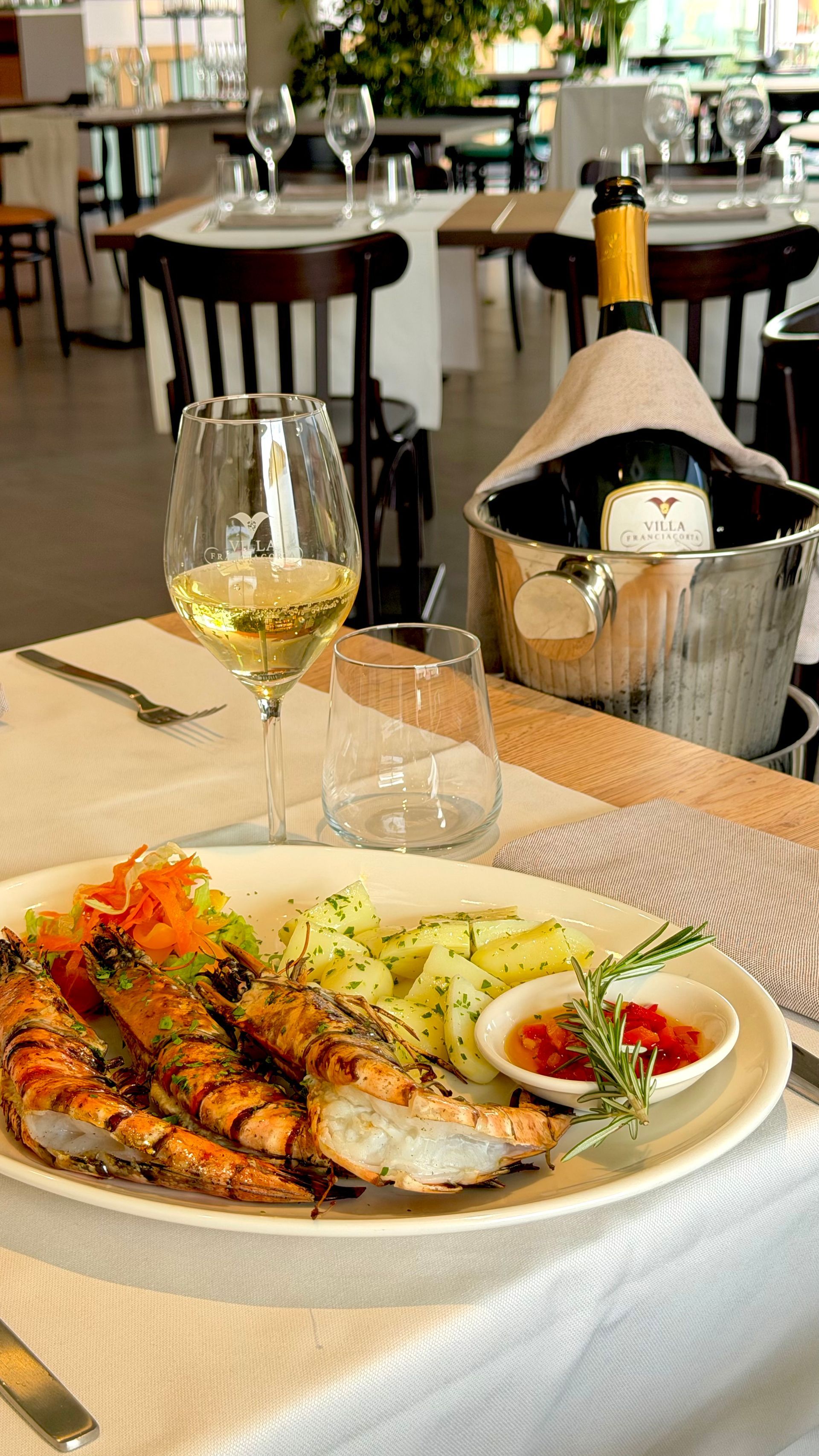 Persone che mangiano pasta e pane a tavola con del vino, riprese da una prospettiva in prima persona.