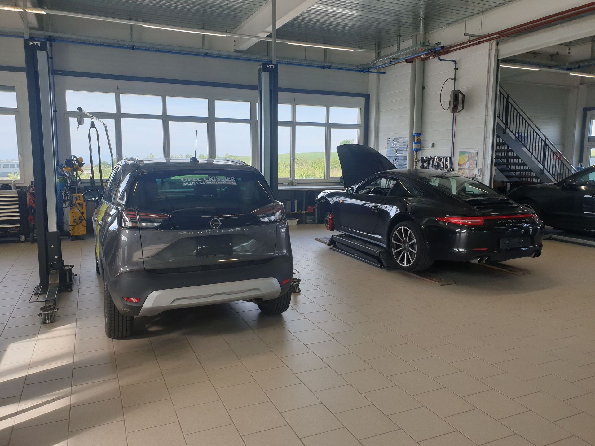 Deux voitures sont garées dans un garage avec les capots relevés.