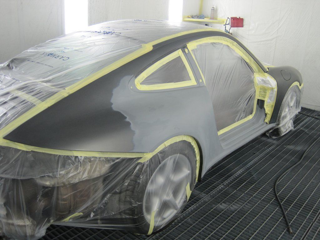 Une voiture est recouverte de plastique pendant qu'elle est peinte dans un garage.