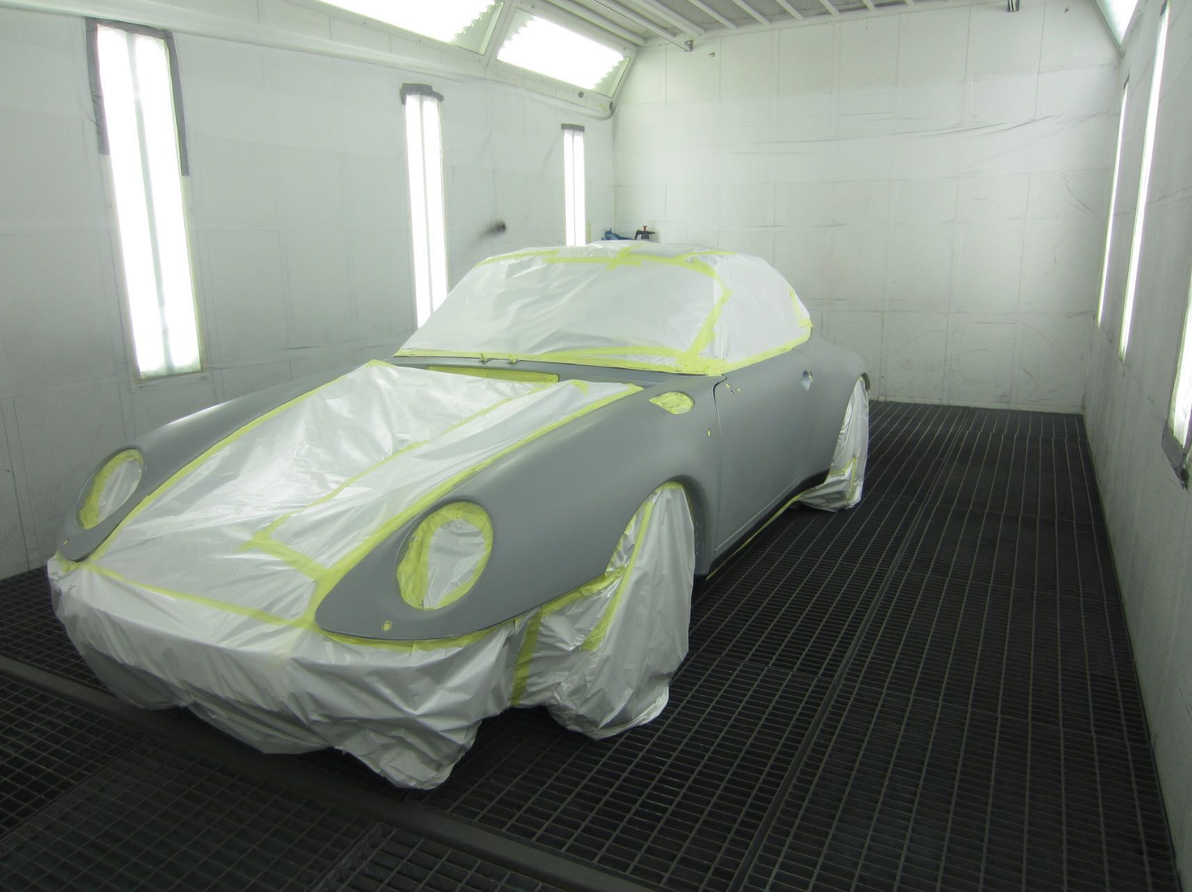 Une voiture est recouverte de plastique dans une cabine de peinture.