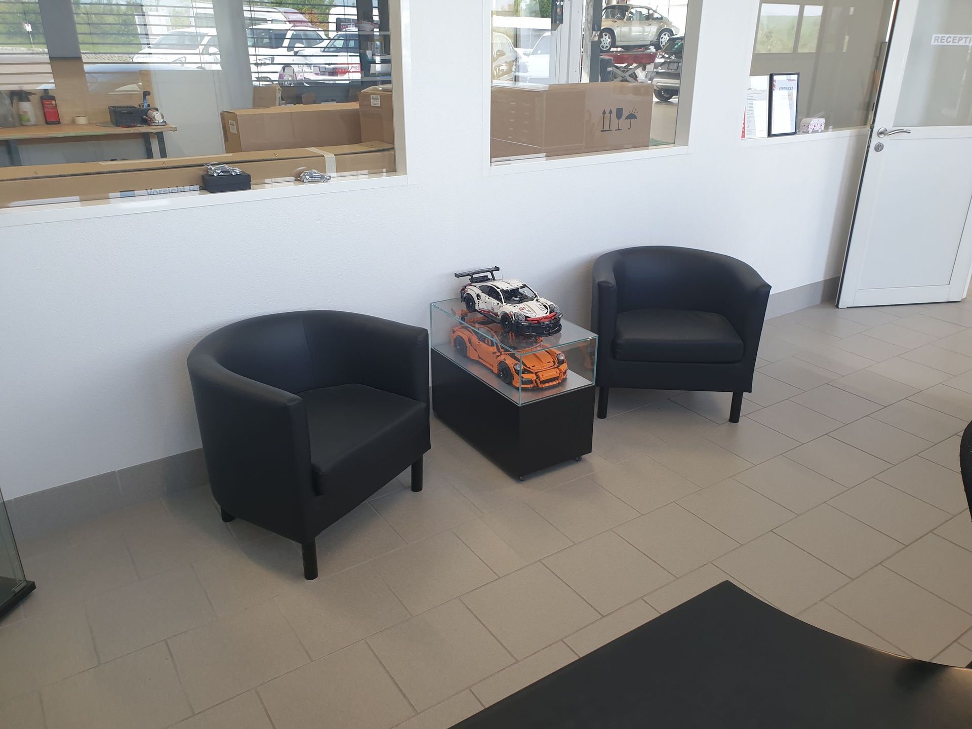 Une salle d'attente avec deux chaises et une maquette de voiture sur une table.