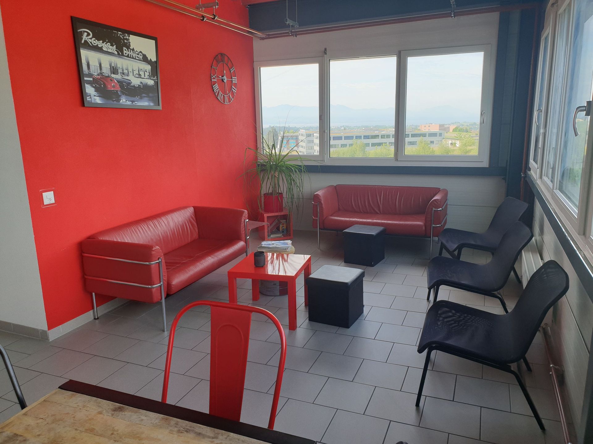 Un salon avec un canapé rouge et des chaises