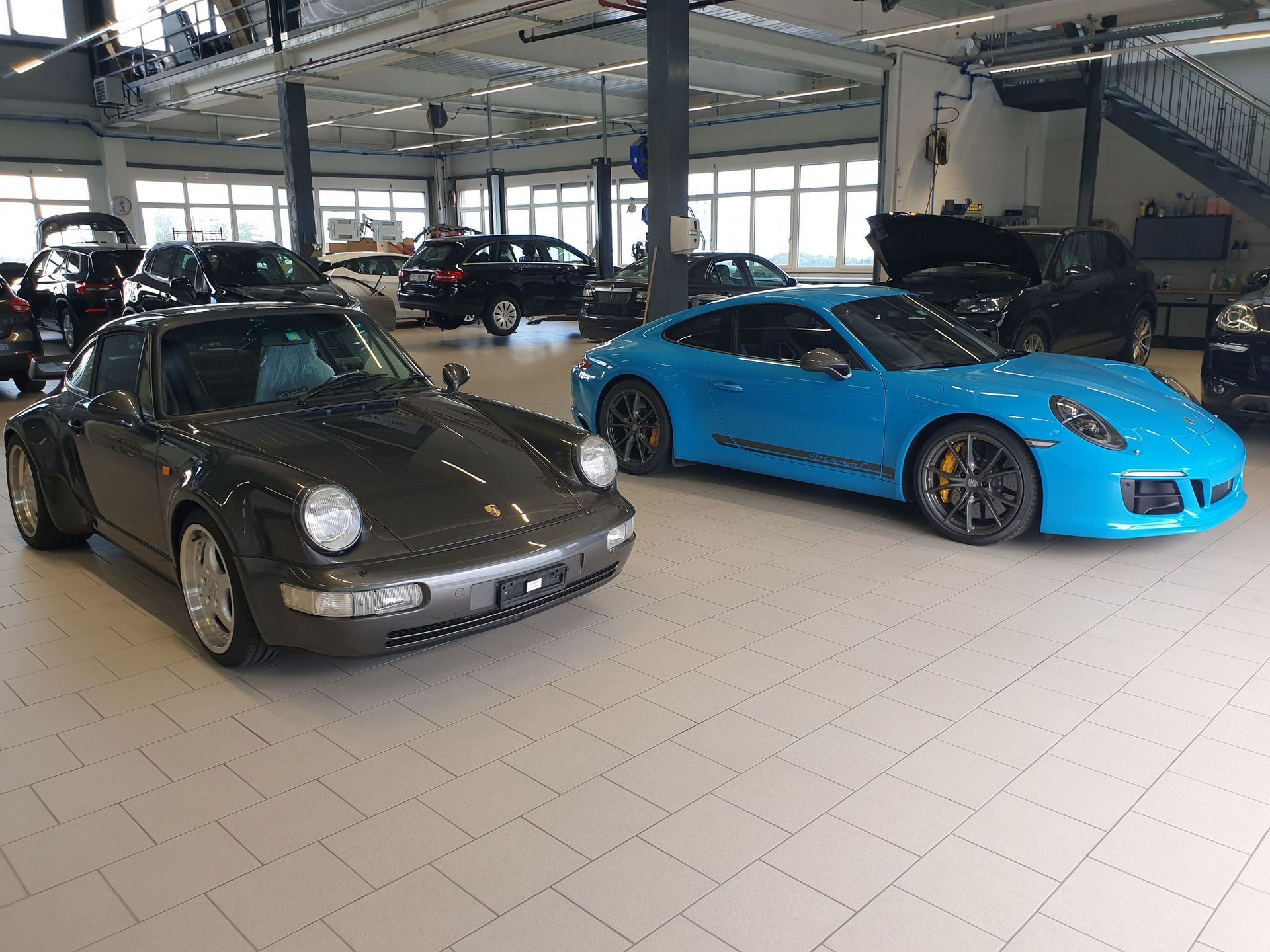 Deux voitures Porsche sont garées dans une salle d'exposition.