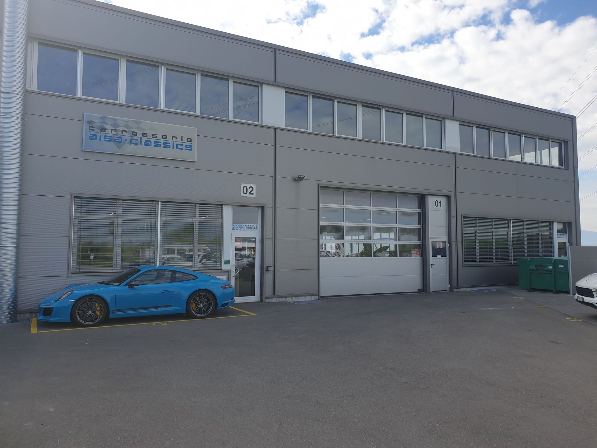 Une voiture de sport bleue est garée devant un grand bâtiment.