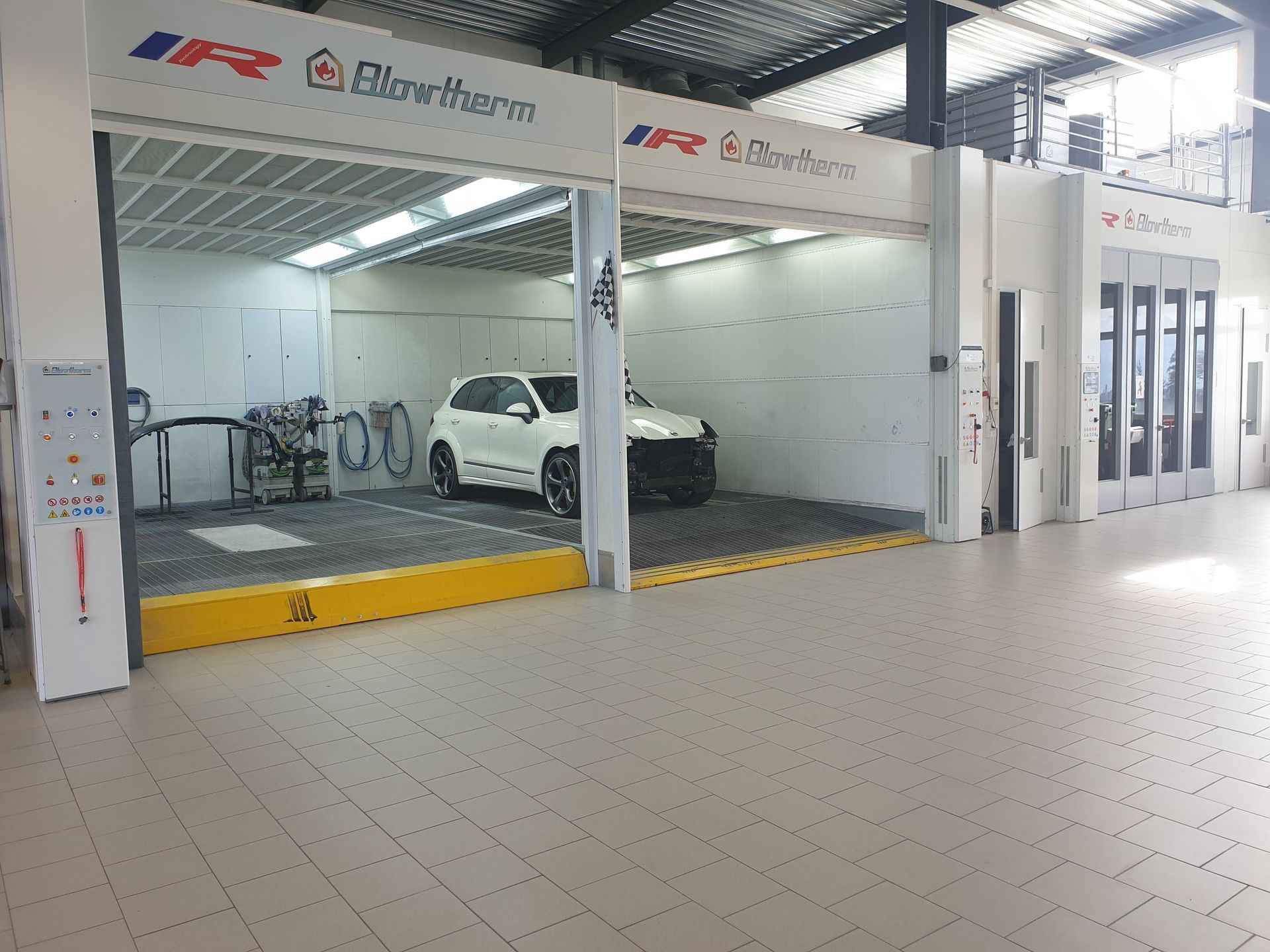 Une voiture est assise dans une cabine de peinture dans un garage.