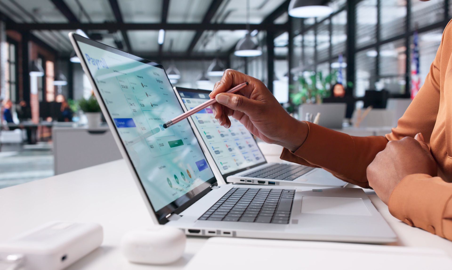 Une personne désigne des données analytiques sur un ordinateur portable dans un bureau lumineux.
