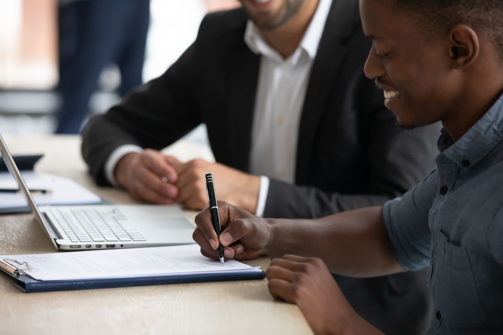 Deux collègues discutent d'un document à une table, un ordinateur portable et un cahier.