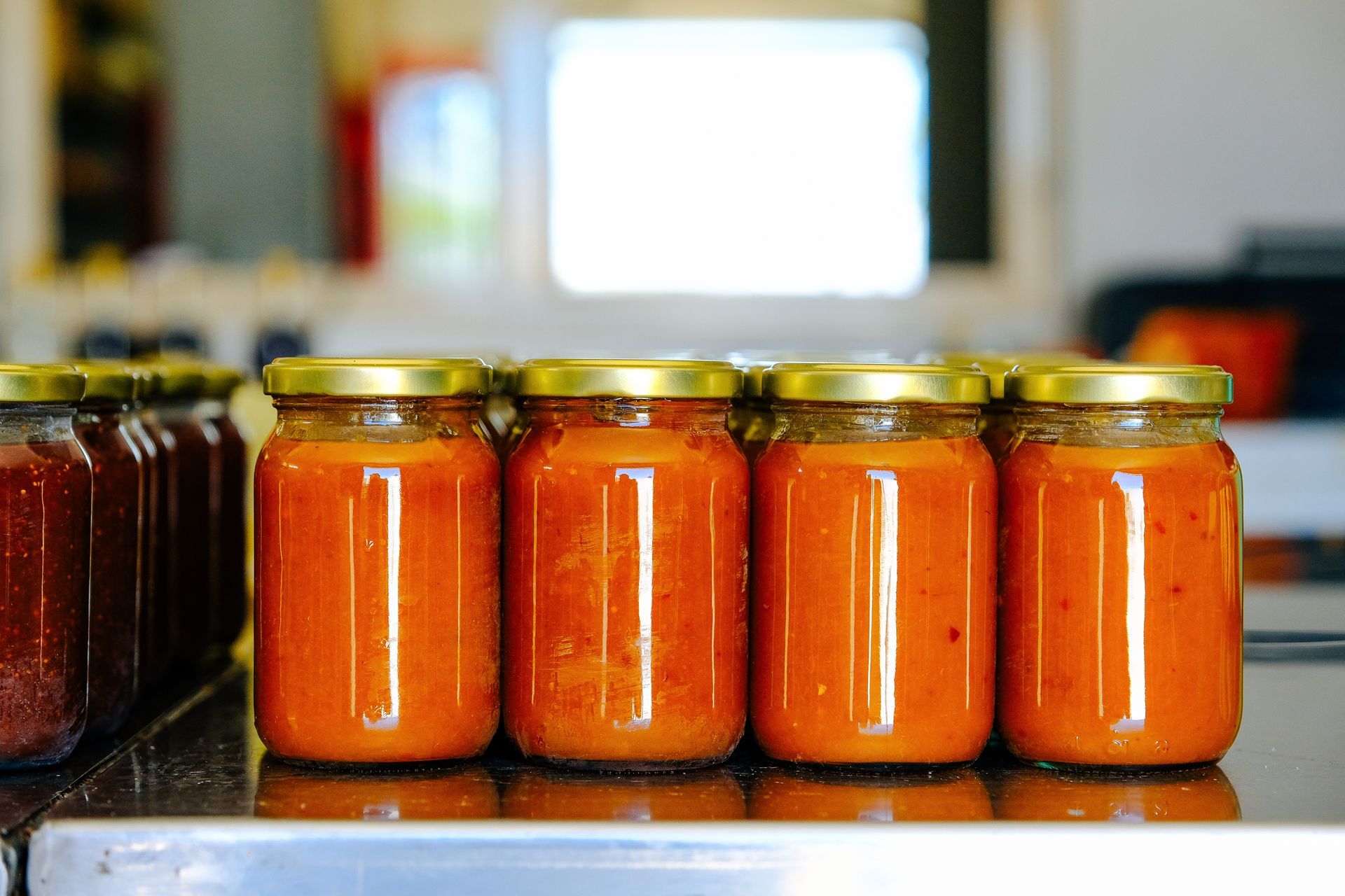 Des bocaux de sauce alignés sur un comptoir dans une cuisine.