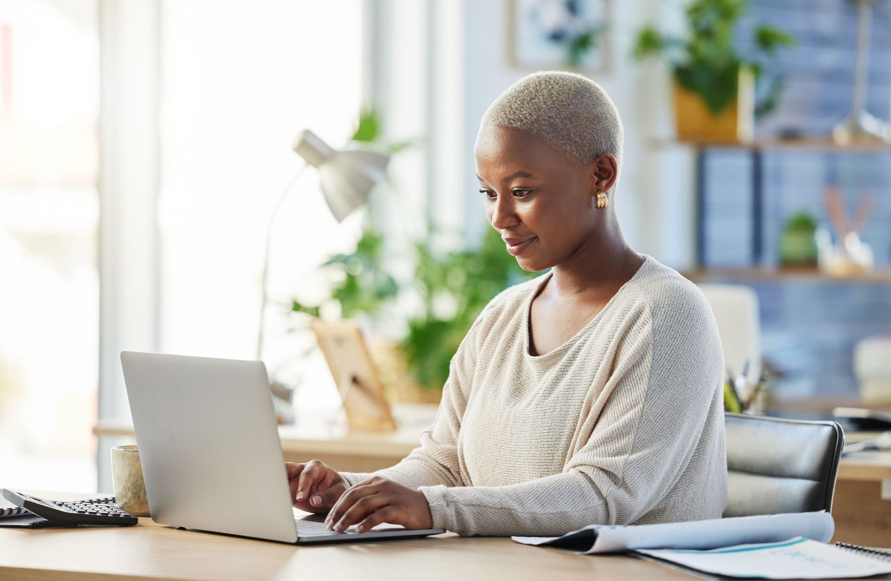 Une personne travaillant sur un ordinateur portable à un bureau dans un bureau à domicile lumineux.