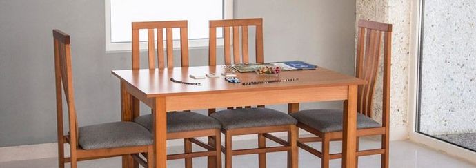 Una mesa de comedor de madera y sillas en una habitación al lado de una ventana.