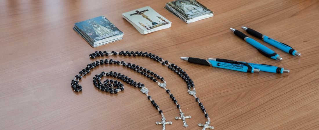 Una mesa de madera cubierta con un rosario, bolígrafos y cerillas.