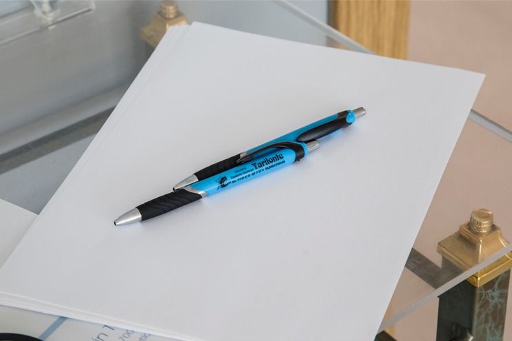 Un bolígrafo azul está sobre una hoja de papel.