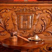 Una mesa de madera con un mazo de juez y un escudo de armas sobre ella.