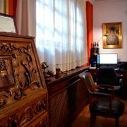 Una habitación con una cómoda, una silla, una computadora y un cuadro en la pared.