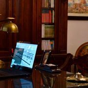 Una computadora portátil está colocada encima de un escritorio de madera en una biblioteca.