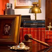 Un mazo de juez de madera está sobre una mesa al lado de una pila de libros.