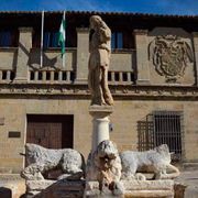 Una estatua de una mujer parada junto a dos leones frente a un edificio.