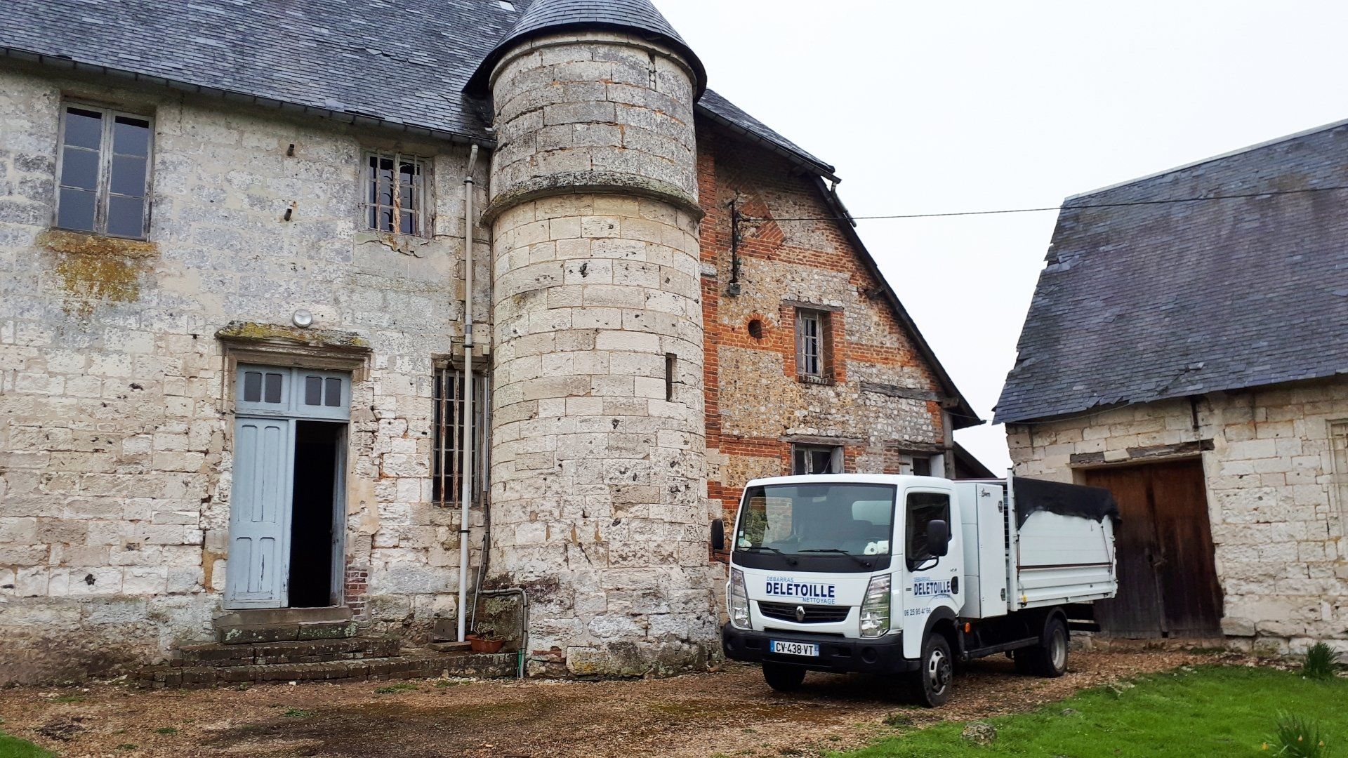 Un camion stationné devant une vieille maison en pierre.