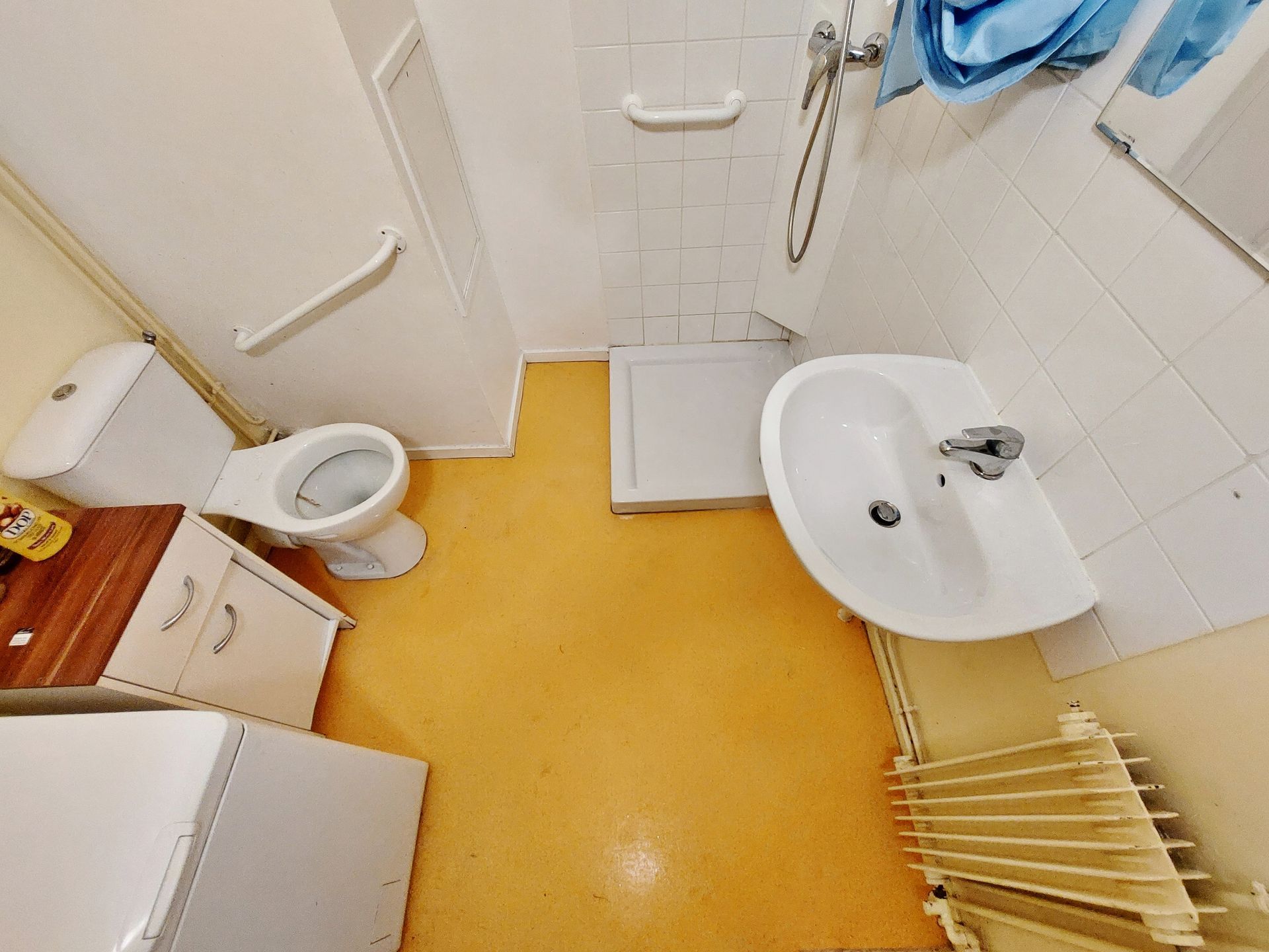 Une petite salle de bains propre et vide au sol jaune.
