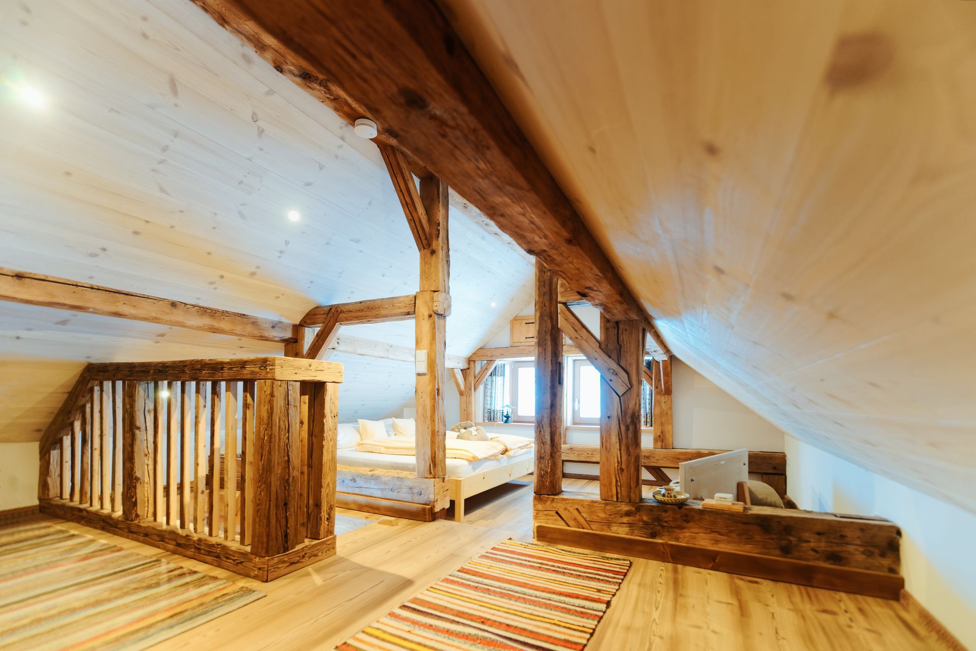 Chambre mansardée en bois avec poutres apparentes et un lit.