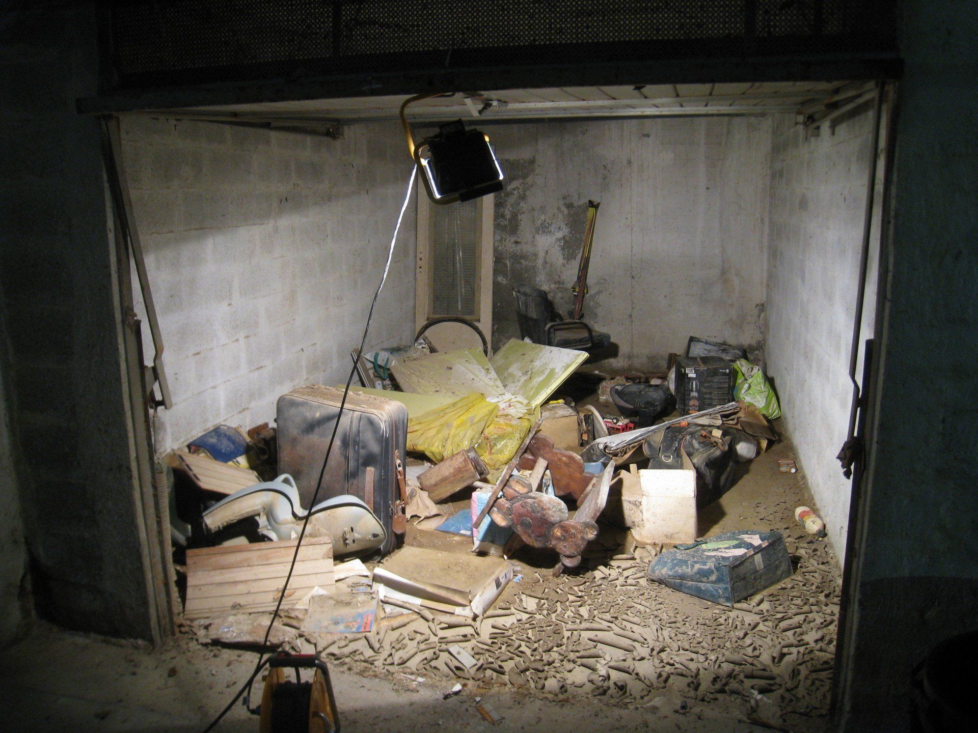 Un garage avec de nombreux objets et déchets au sol.
