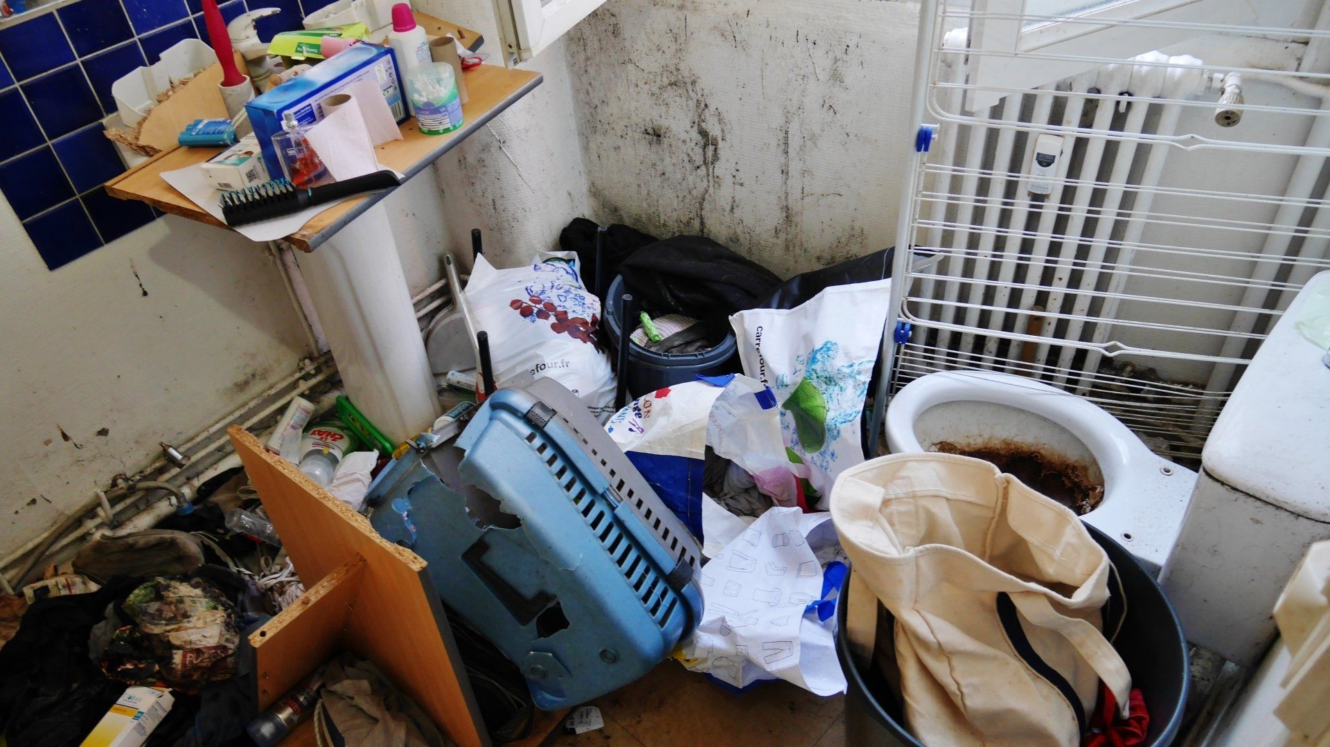 Salle de bains très sale et encombrée par des déchets.