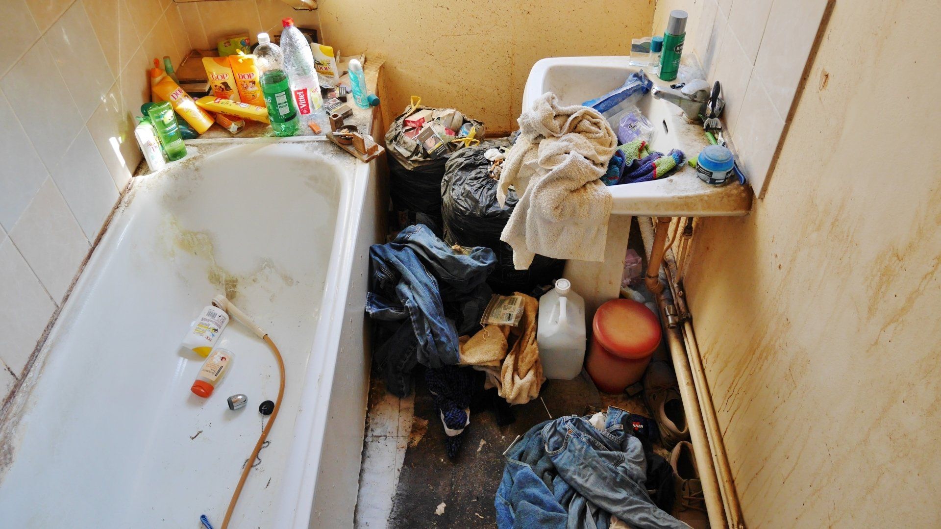 Une salle de bains avec une baignoire encombrée par des déchets.