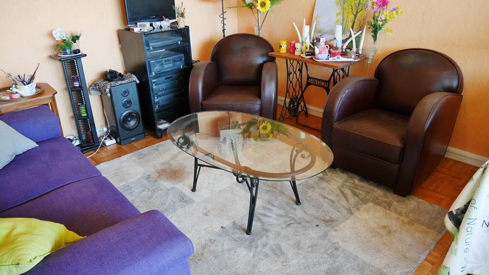 Un salon avec une table en verre entourée de 2 fauteuils et d'un canapé.