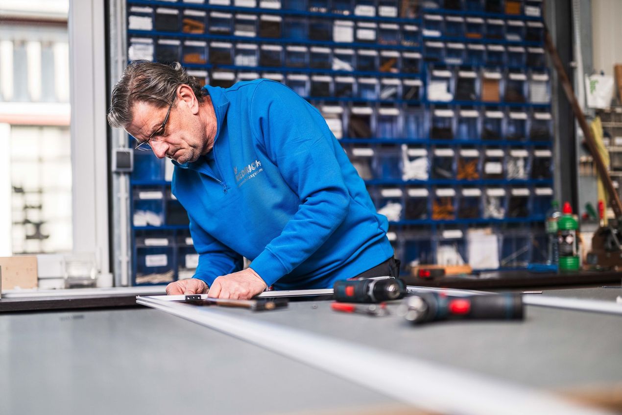 Ein Mann in einem blauen Hemd arbeitet an einem Stück Metall.